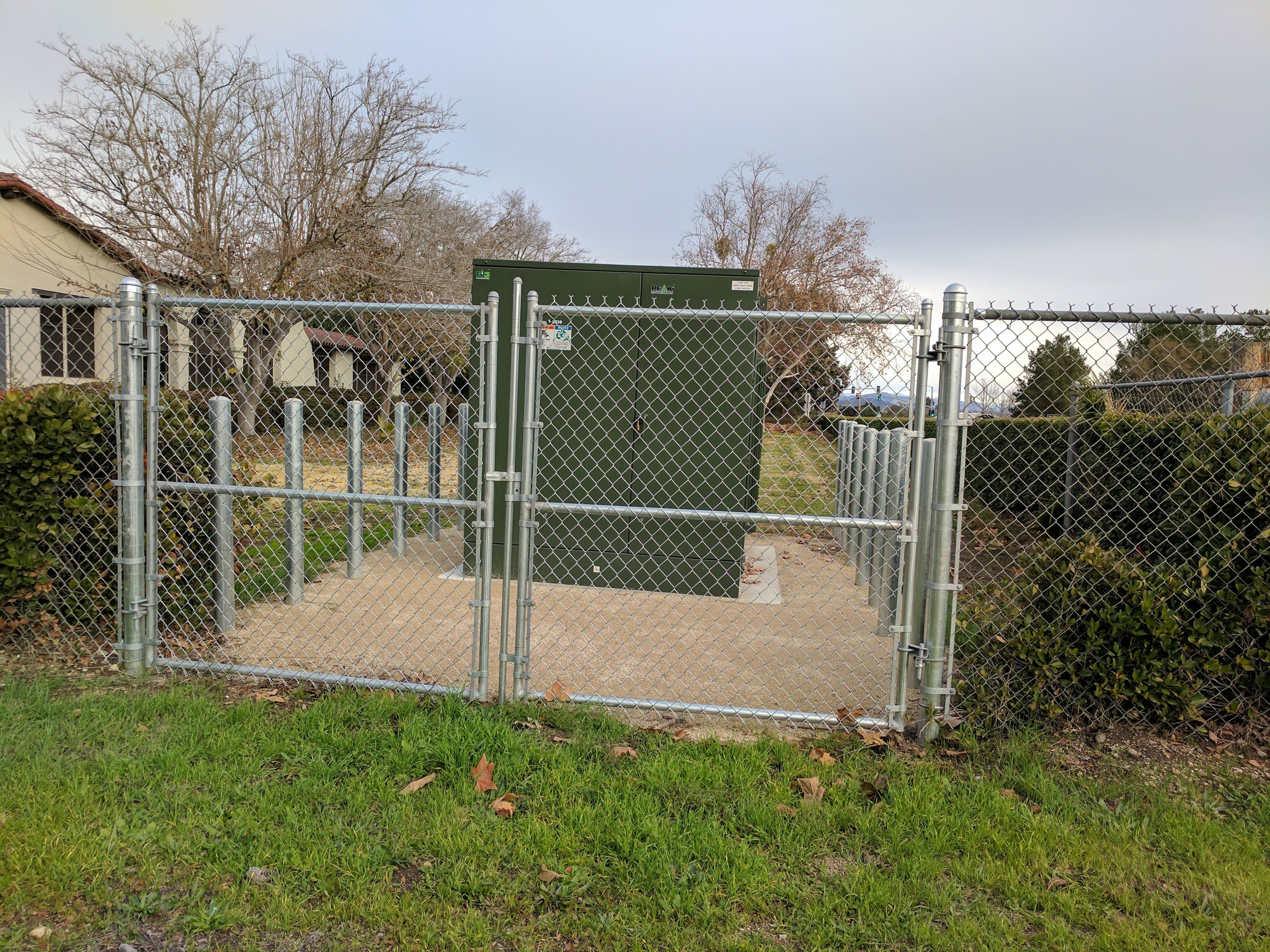 Galvanized chain link security fence with a lockable swing gate protecting an electrical substation and transformer installation