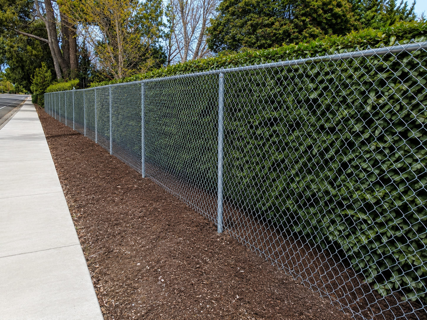 Galvanized chain link boundary fence with round steel posts installed for residential and commercial property security.